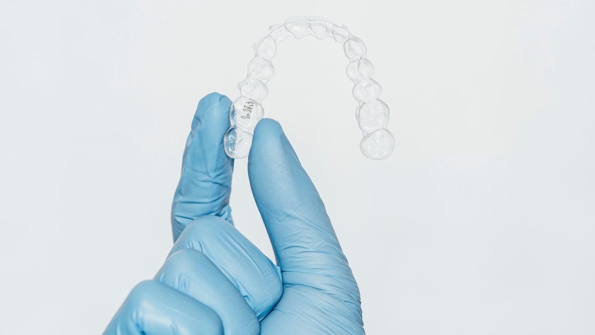 Thin clear thermoplastic occlusal guard held at the dental lab bench
