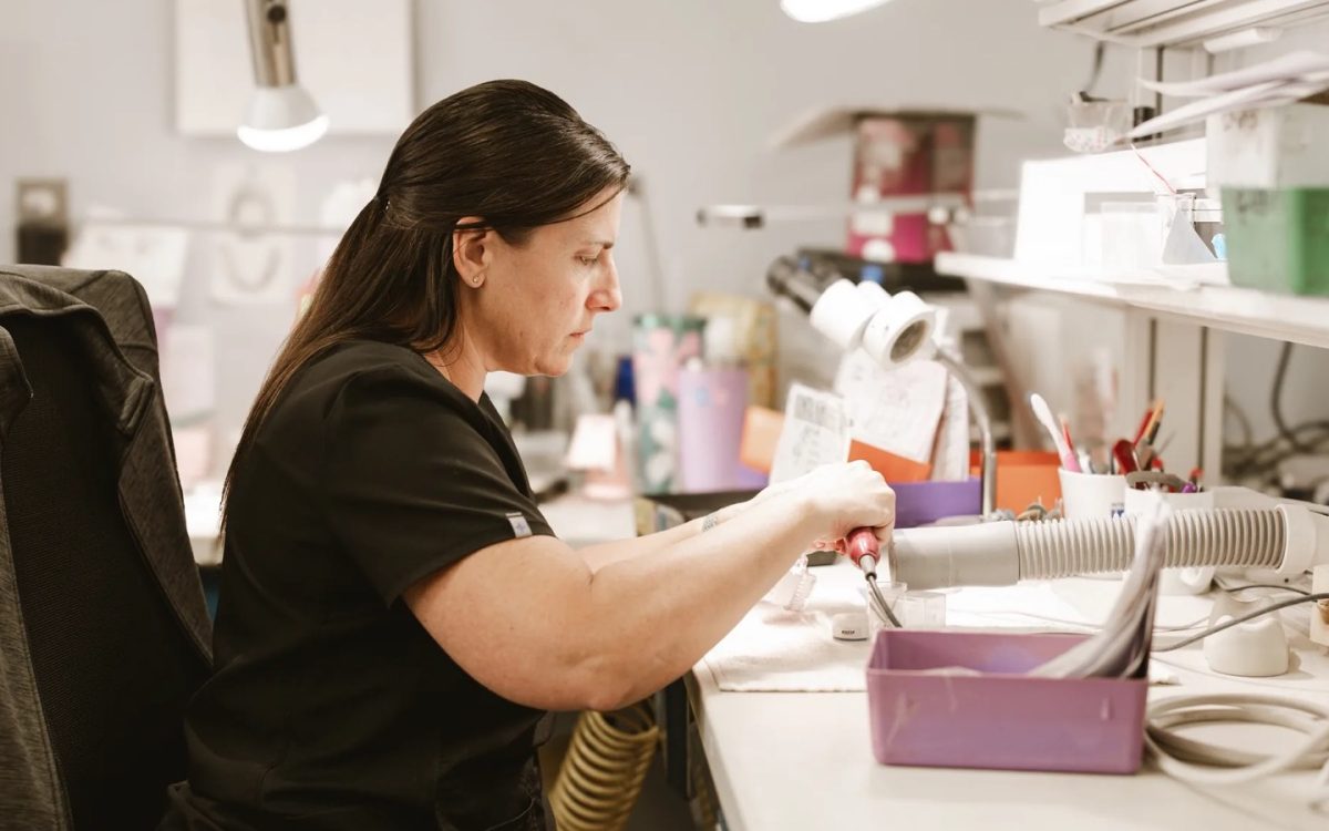 IDA technician working a case with a handpiece at the laboratory bench in Tulsa